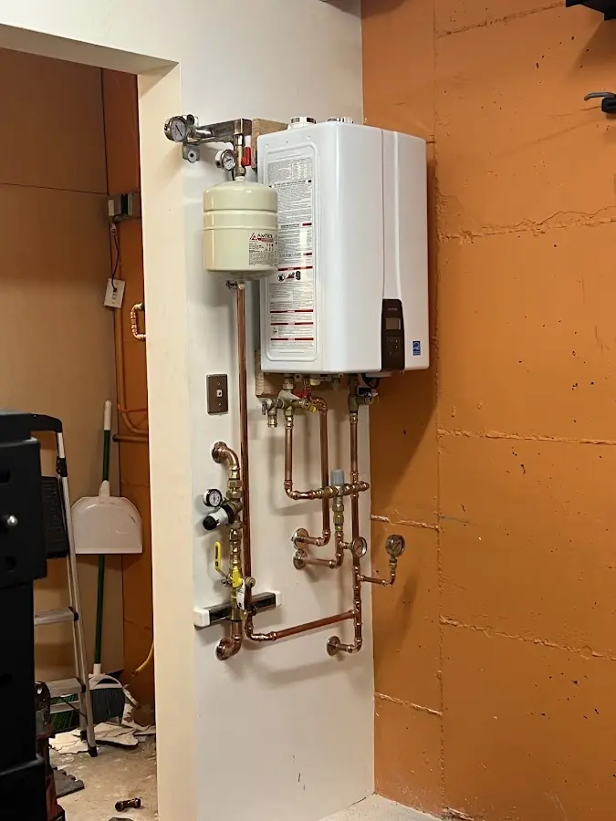 Plumbing technician inspecting water heater connections in Tremonton